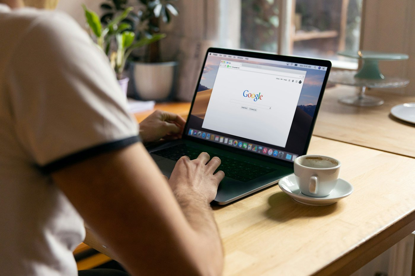 Person typing a search into Google on a laptop